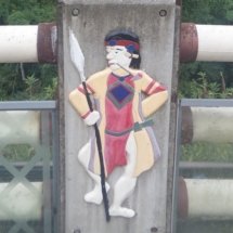 A fence design of a person with a spear wearing red and gold.